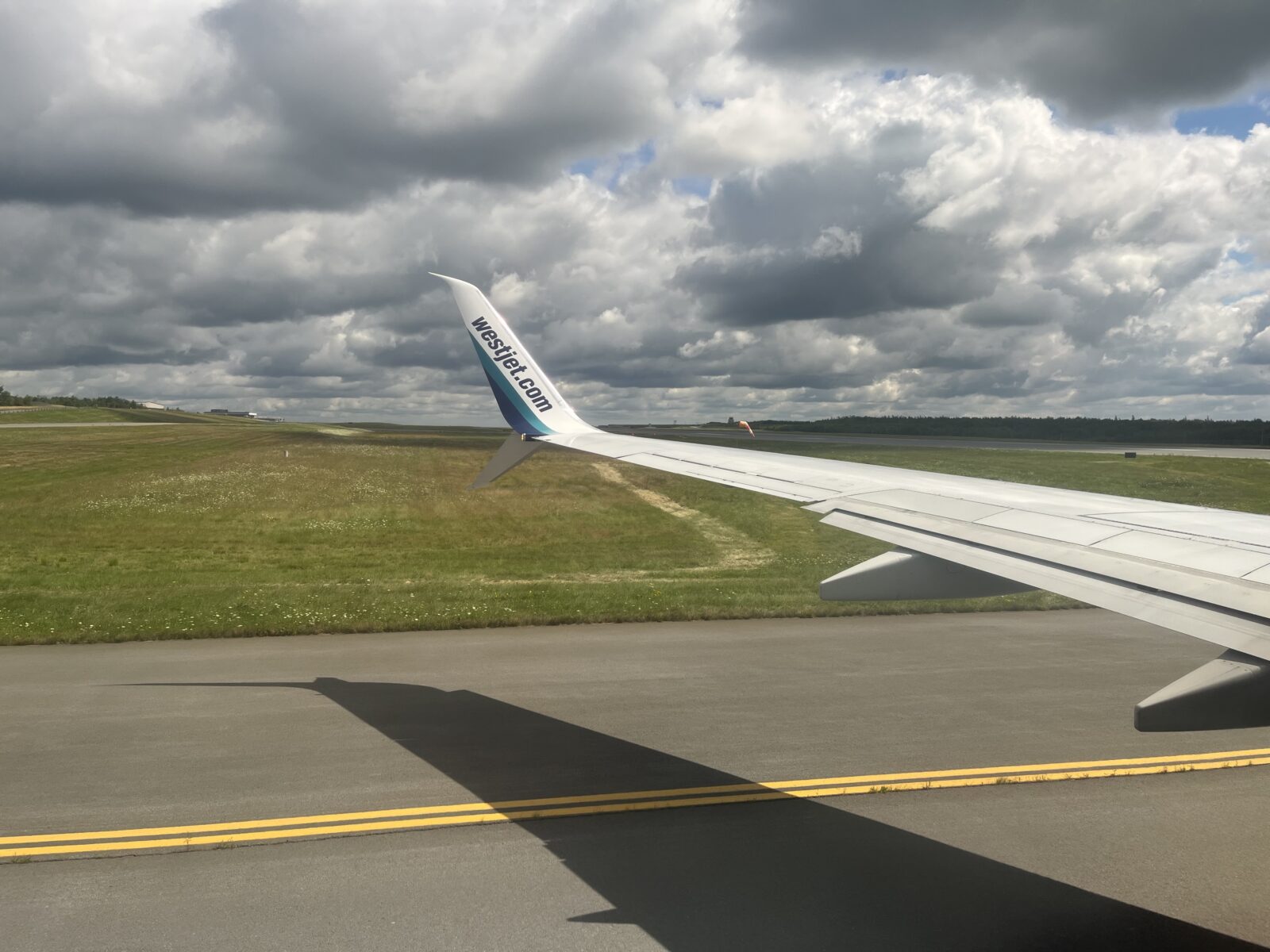 WestJet airplane wing with Halifax runway and air traffic control tower in the background
