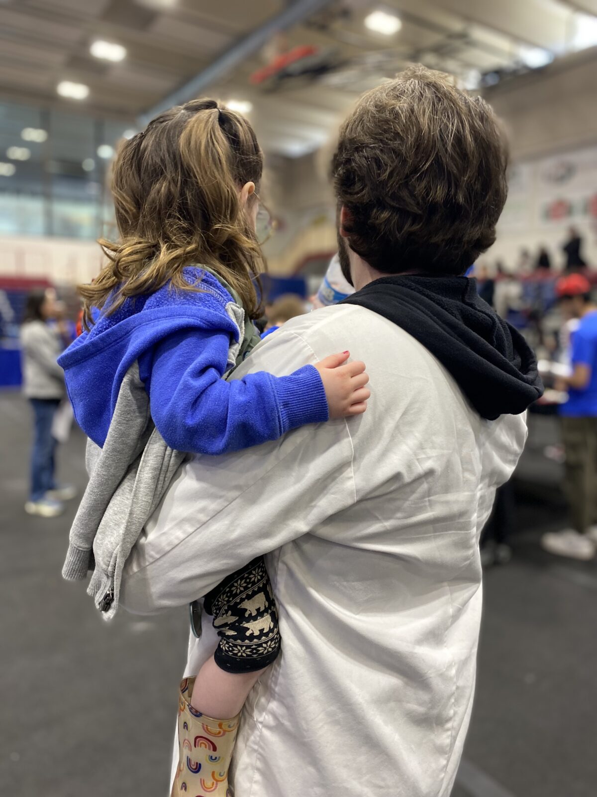 Head referee Griff in a white lab coat with Gwen helping at the Lego robotics competition.